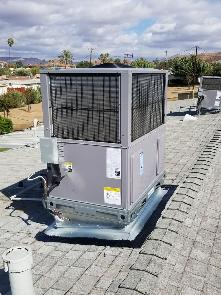 A rooftop package unit installed on a tile roof, valley hills behind