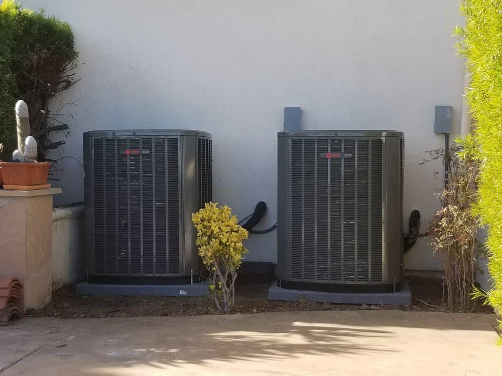 Two condensers Rizzo installed side by side against a stucco wall