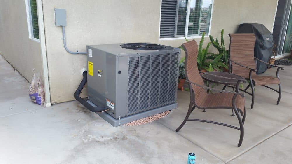 A condenser set on a pad at the corner of a patio with the line set run to the wall