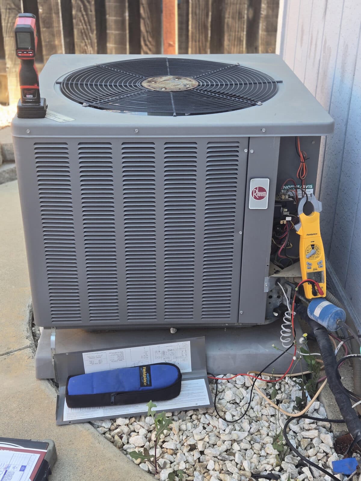 A Rheem condenser with a clamp meter and Fieldpiece probe hooked up during a service call