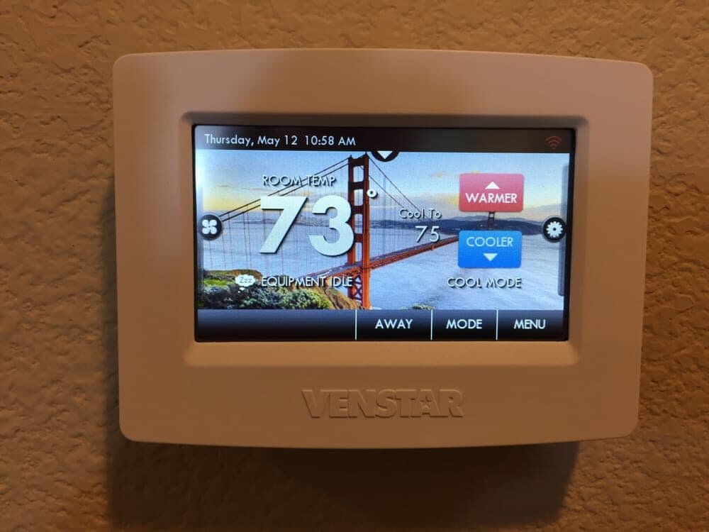 A Venstar colour touchscreen thermostat mounted on an interior wall