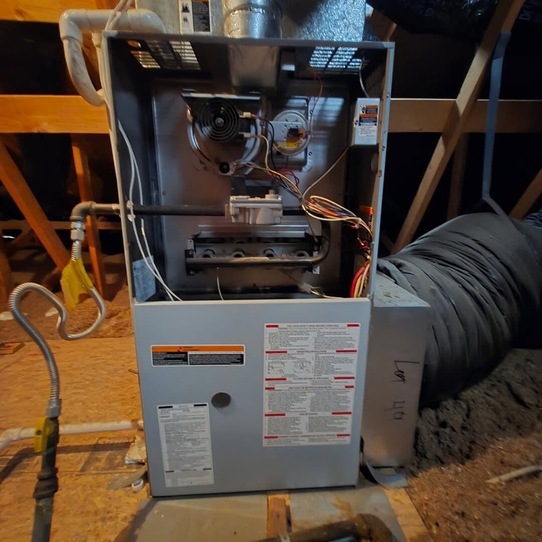 A furnace opened up in an attic with the burner assembly exposed for inspection