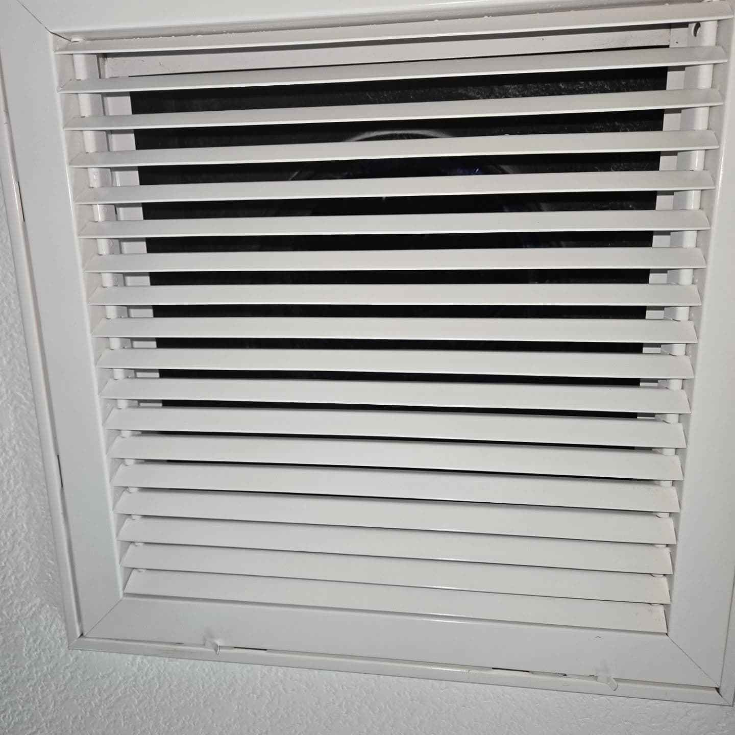 The louvred return air grille back on the wall, cleaned, with the filter behind it