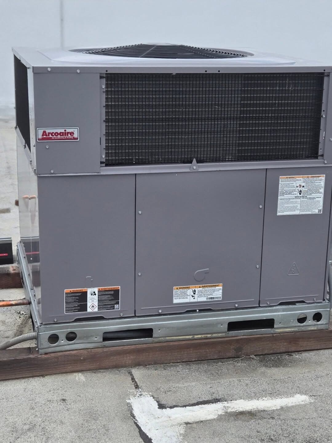 An Arcoaire package unit standing on its curb on the finished roof