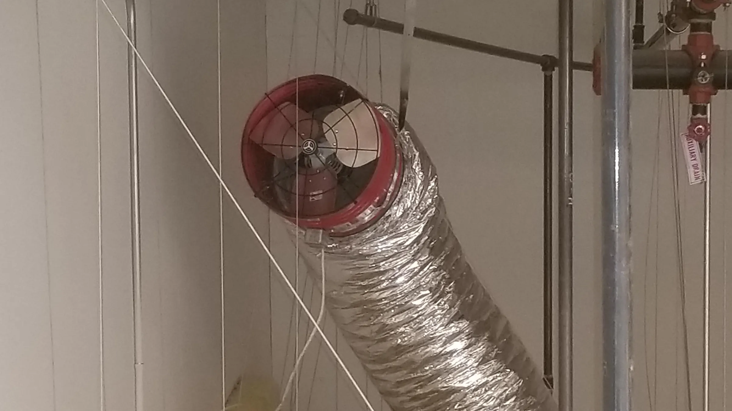 A ducted whole-house fan mounted above the ceiling with insulated flex duct run to the damper